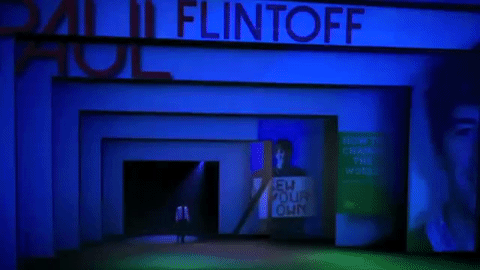 Moving image of man walking across large stage with his name Flintoff visible
